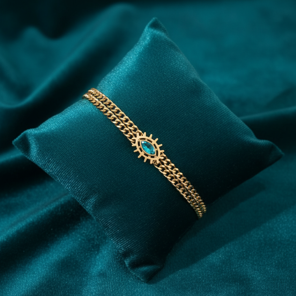 Gold bracelet with turquoise evil eye centerpiece on slanted square teal cushion