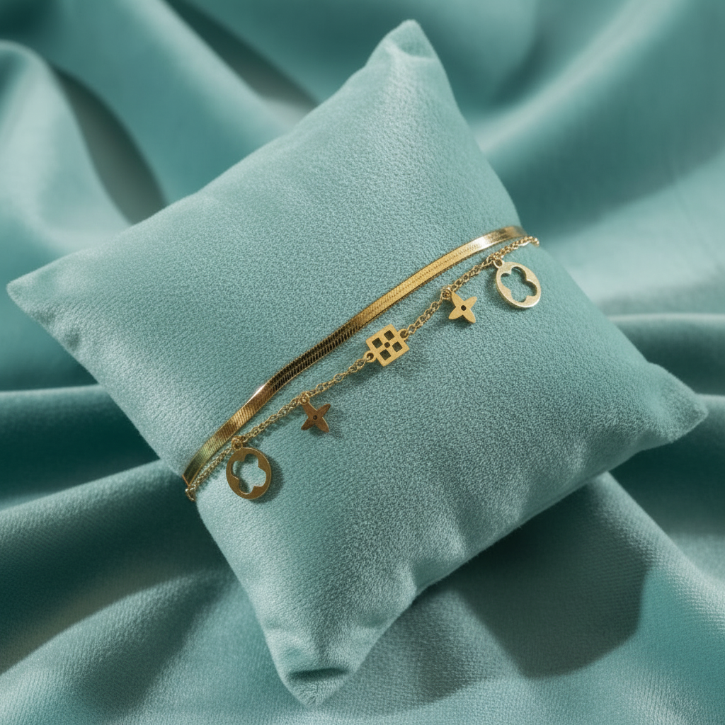 Gold double-layered herringbone and charm bracelet on slanted square teal cushion