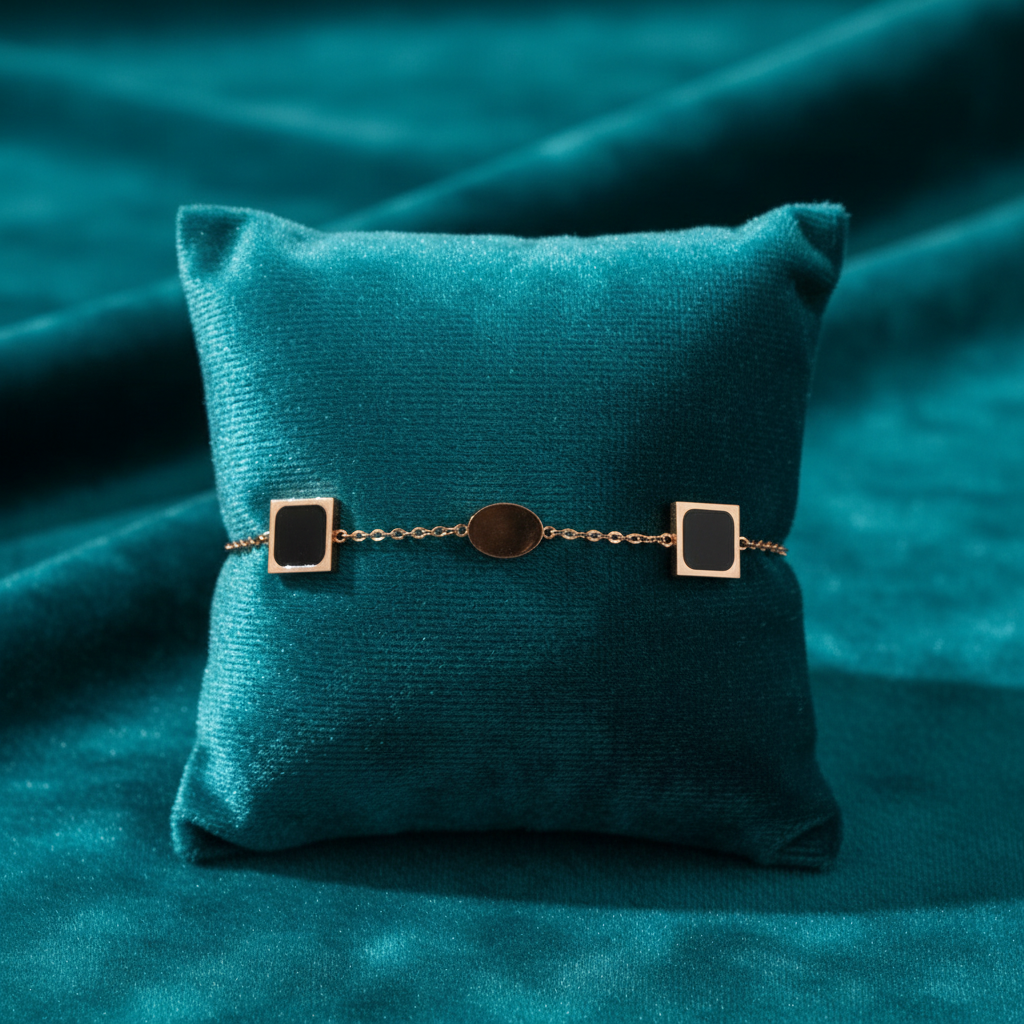 Rose gold and black enamel geometric bracelet on teal jewelry cushion with teal background