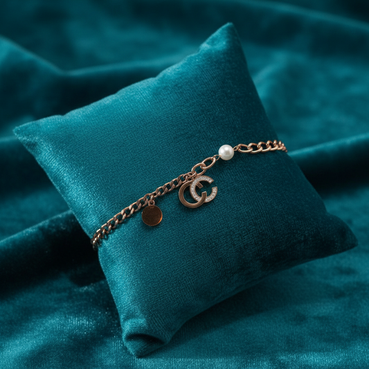 Rose gold bracelet with pearl, crescent moon, and disc charms on slanted square teal cushion