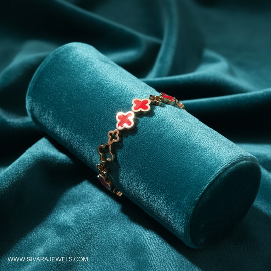 Rose gold quatrefoil bracelet with two red enamel accents on teal cushion