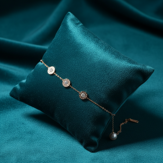 Rose gold three Roman numeral medallions and pearl bracelet on slanted square teal cushion